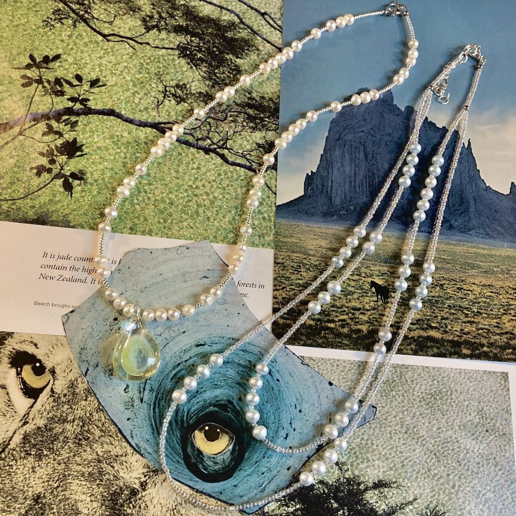 Two variations of styles of freshwater pearl necklaces. The left hand style is one-of-kind featuring a handmade glass pendant. The style on the right is a long, doubled stranded bib-style necklace strung with pale blue pearls, and available in other colors in person.